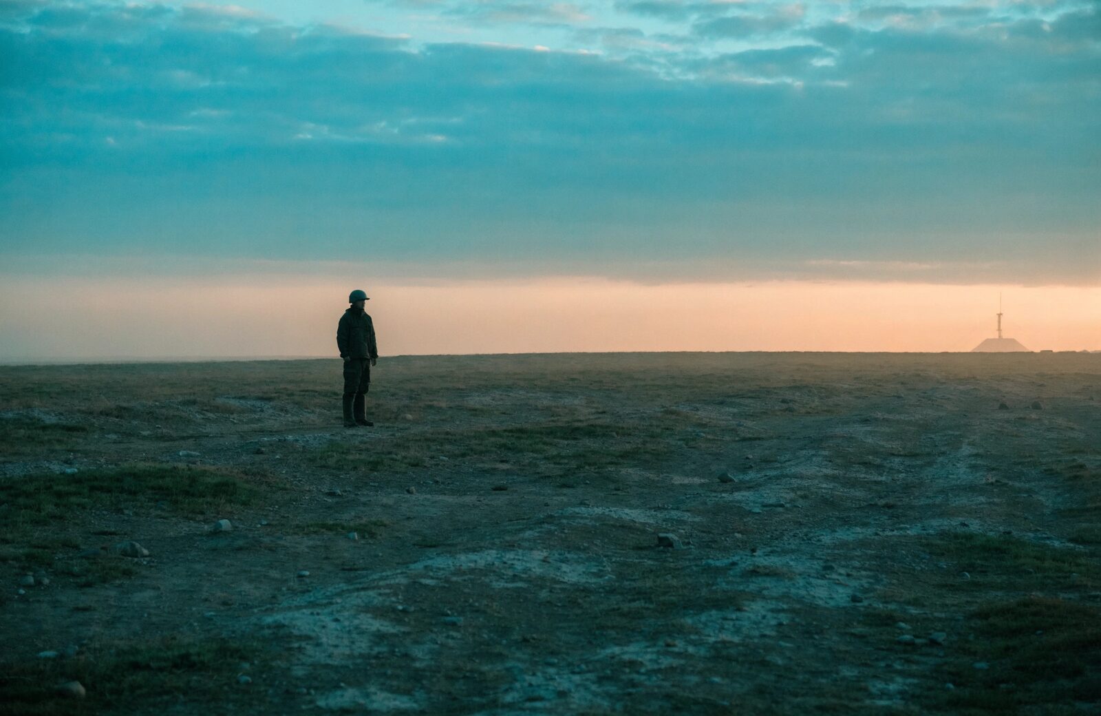 A figure keeping watch over a quiet landscape at dusk.